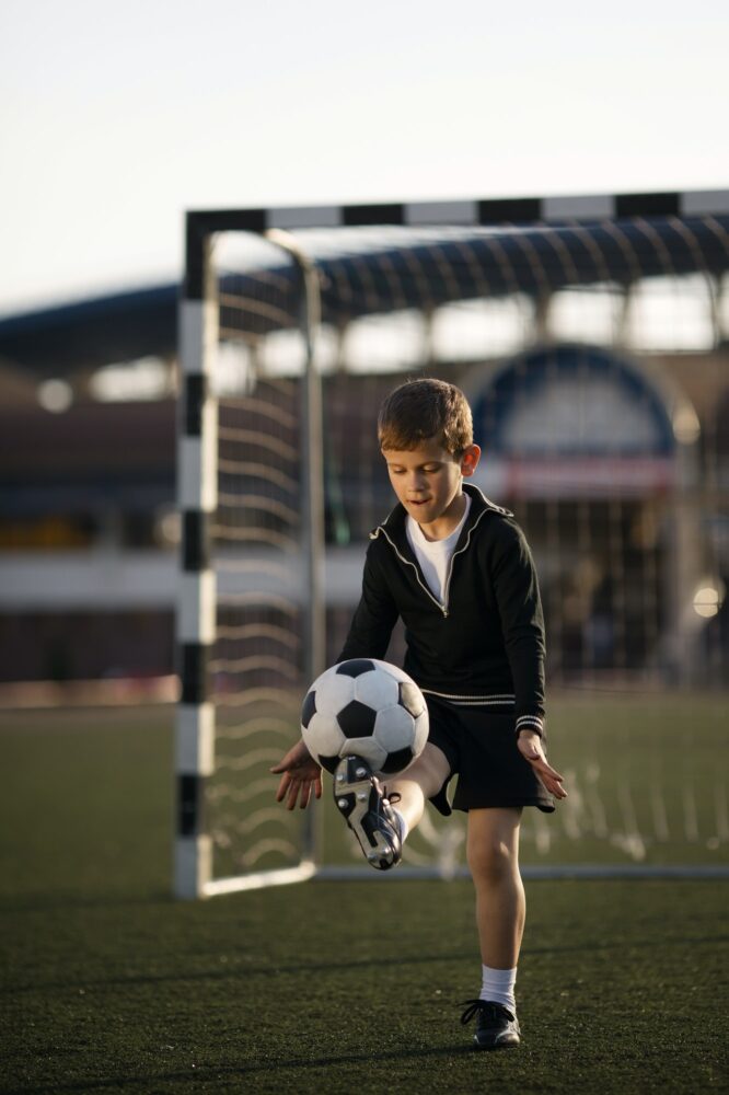 boy plays football on stadium